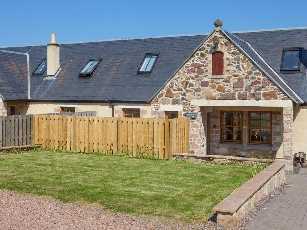a stone house with a wooden fence and a yard at Honeysuckle Cottage - Ukc6255 in Linlithgow