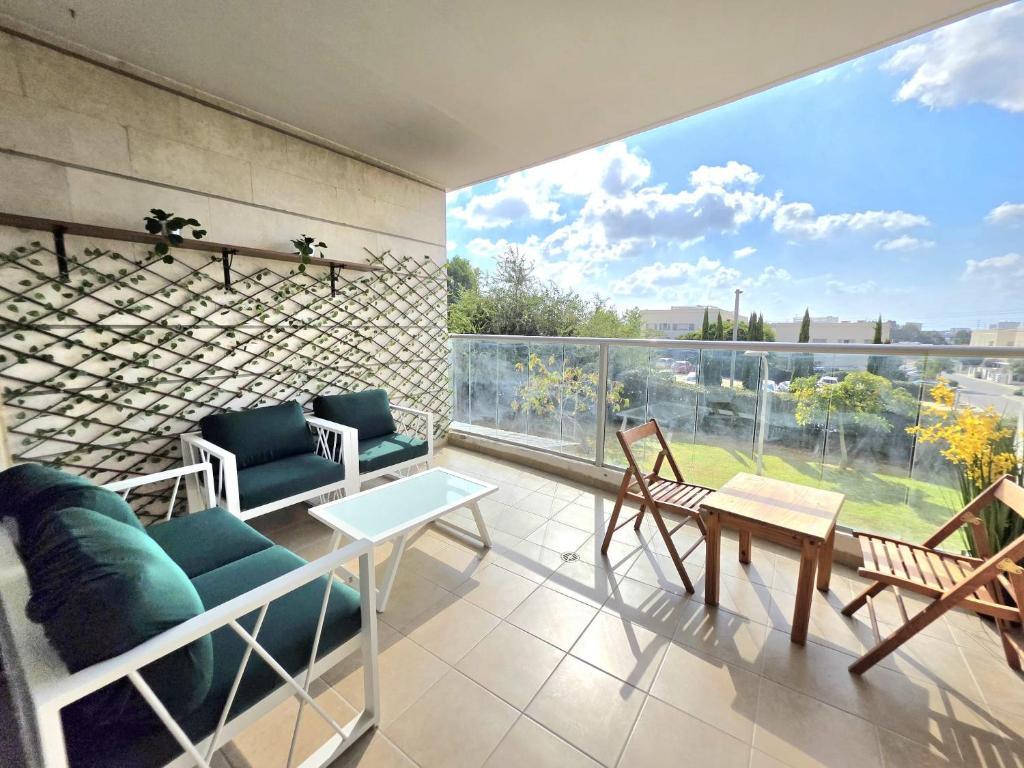 a balcony with chairs and a table and a large window at Your home in Pardes Hanna in Pardes H̱anna