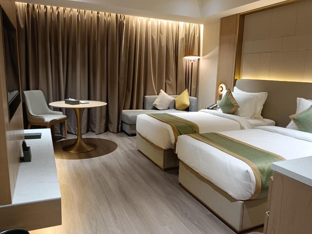 a hotel room with two beds and a table at The Bansara Royal in Kātoya
