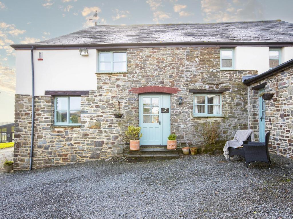 a stone house with a blue door and a bench at Jasmine Cottage - Ukc4694 in Kilkhampton