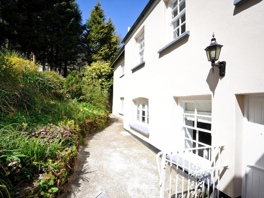 a white house with a bench on the side of it at Corner Cottage - Ukc4962 in Tawstock