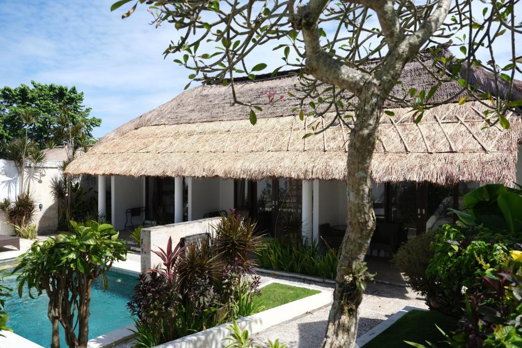 a resort with a swimming pool and a thatch roof at Villa Leelavadee in Uluwatu