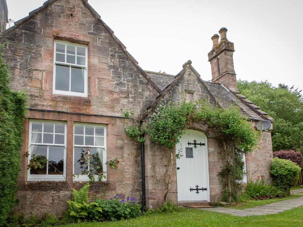 an old brick house with a white door at Drumlanrig Mains Cottage - Uk7174 in Carronbridge