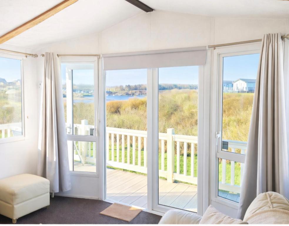 a bedroom with doors open to a balcony with a view at Riverscape Northumberland in Ashington