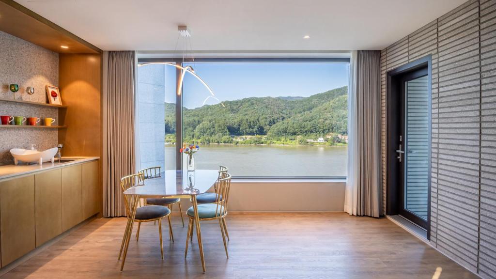 a dining room with a table and a large window at Gapyeong Laputa Resort in Gapyeong