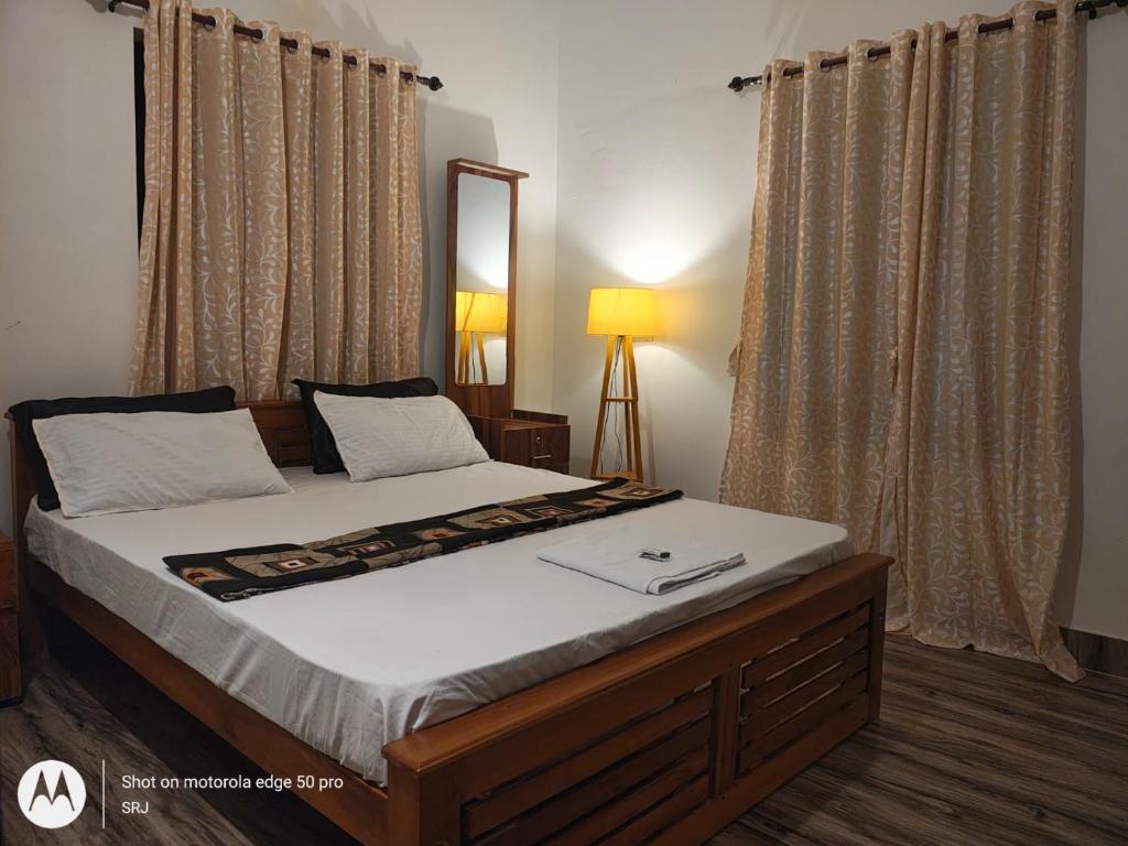 a bedroom with a bed with a mirror and curtains at Sandy Steps in Varkala