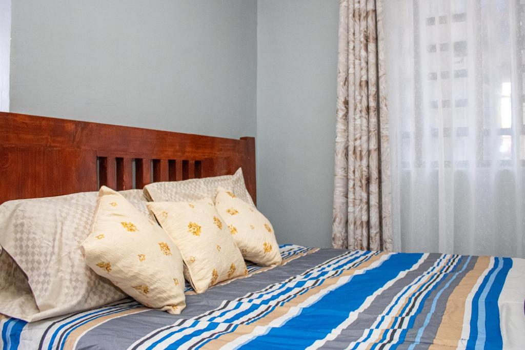 a bed with a wooden headboard and pillows at Ziwa View studio Apartments in Goat Island