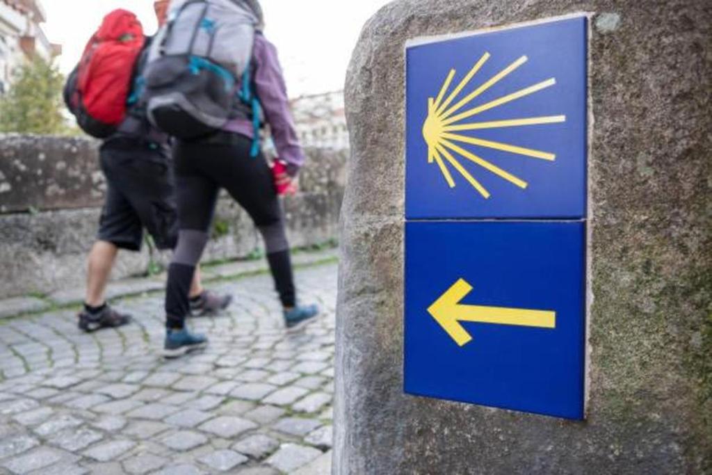 two people with backpacks walking down a street with a sign at Santiago Rooms in Caminha