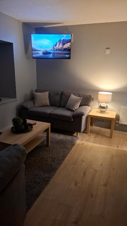 a living room with a couch and a tv on the wall at Apartment 1 at Busy Bee in Daingean