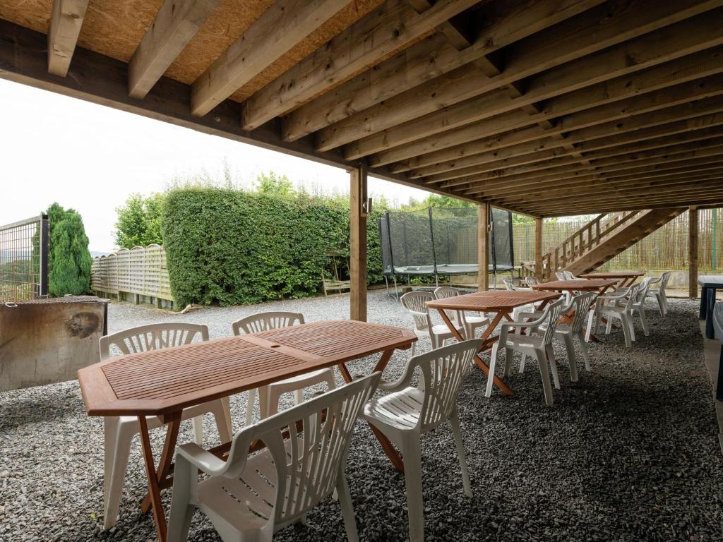 uma fileira de mesas e cadeiras de madeira sob um telhado em Famililale ideal home for family gatherings em Lierneux