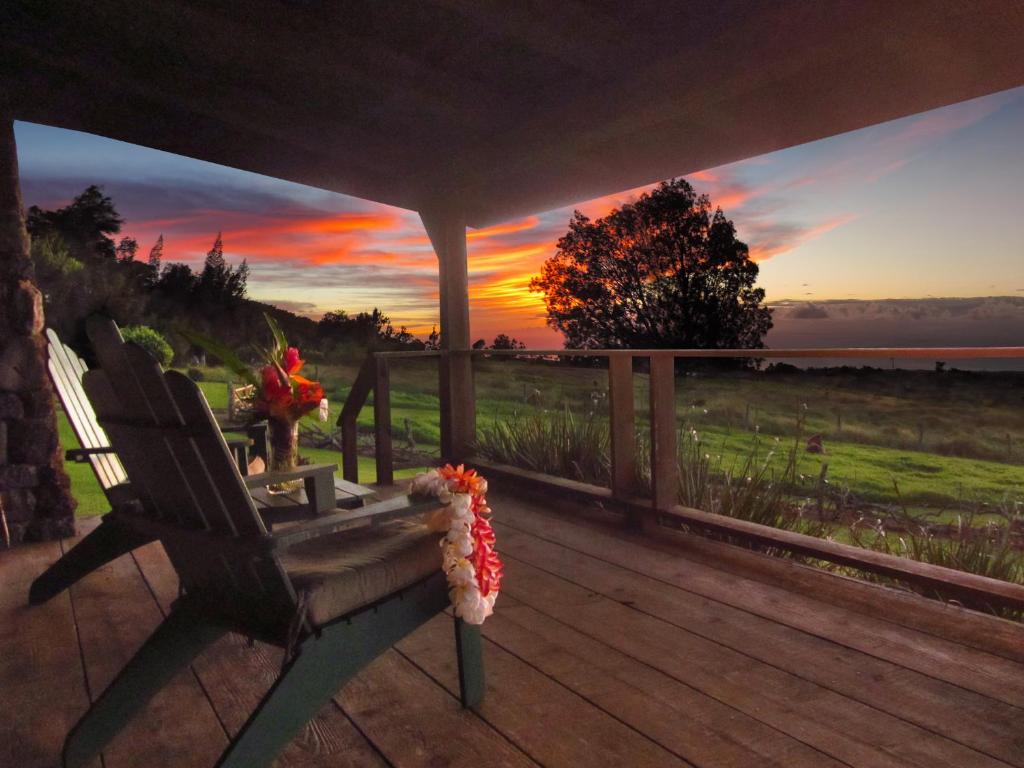 eine Bank auf einem Deck mit Sonnenuntergang im Hintergrund in der Unterkunft Kohala Lodge- Vacation Rental House in Hawi