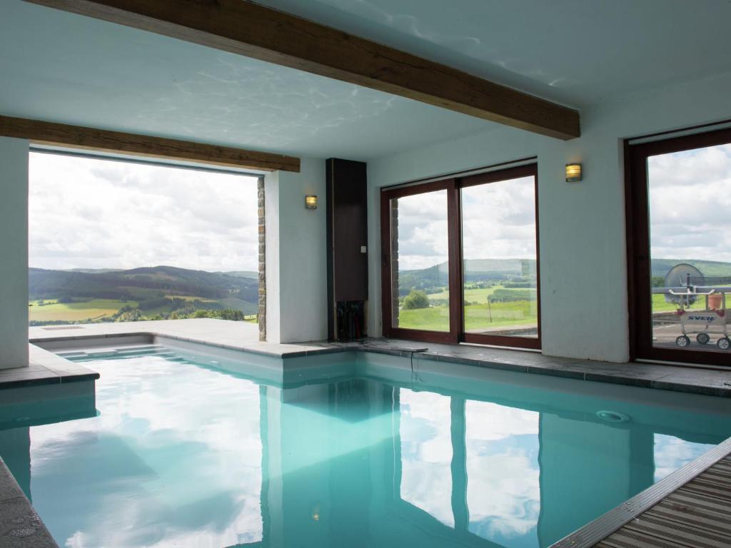 een zwembad met uitzicht op de bergen door de ramen bij Spacious and well cared for house with a panoramic in Habiemont