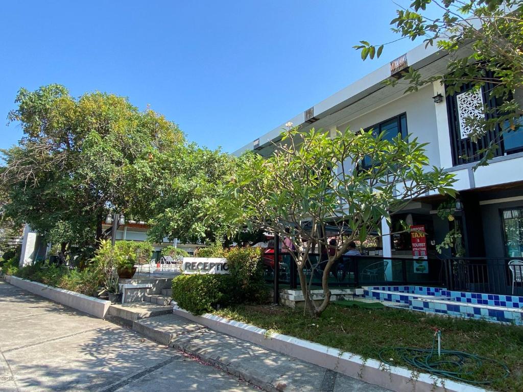 a building with trees in front of a street at Tamnan Resort Pattaya in Ban Nong Chaeng