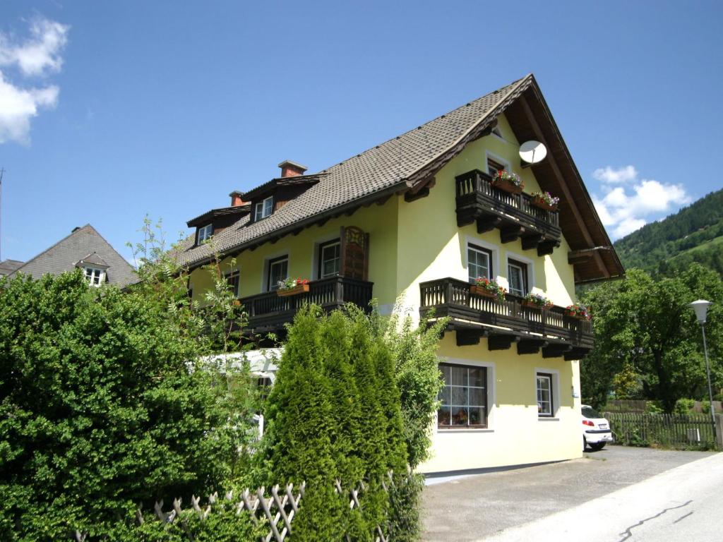 a yellow house with black balconies and trees at Apartment in Feld am See with lake access in Feld am See