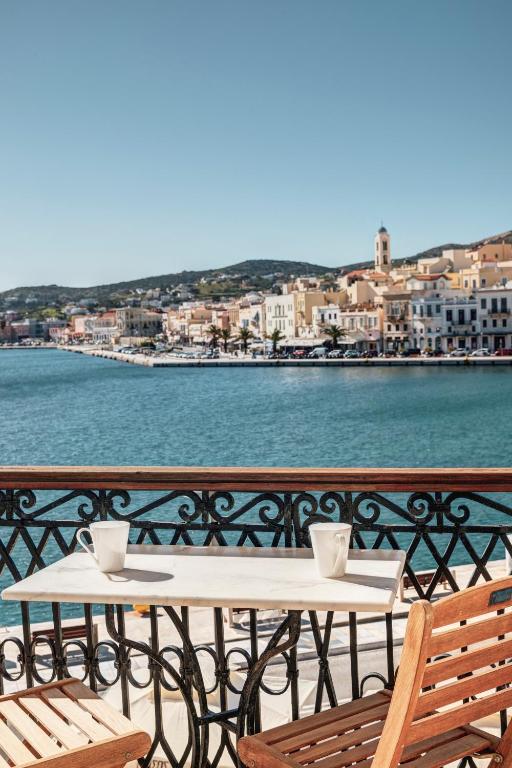 a table and chairs on a balcony with the water at Hotel Aktaion Syros in Ermoupoli