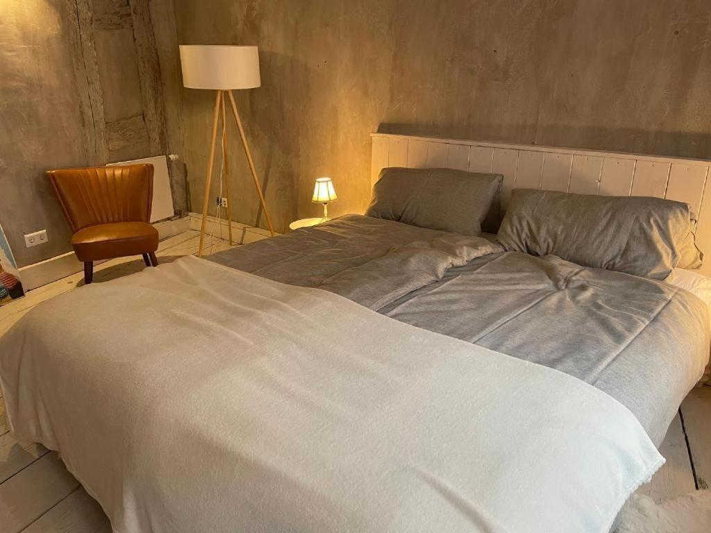a large white bed in a bedroom with a chair at Ferienwohnung "Atelier_1" in Edenkoben
