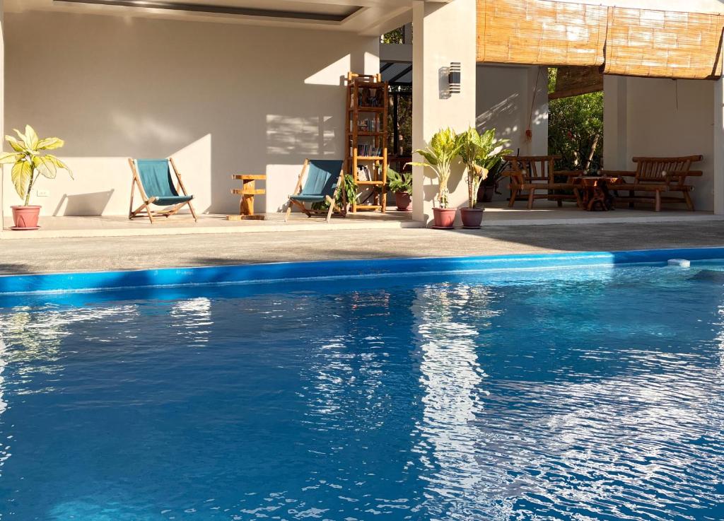 a swimming pool with blue chairs next to a house at The Lazy Tiki in Buenavista