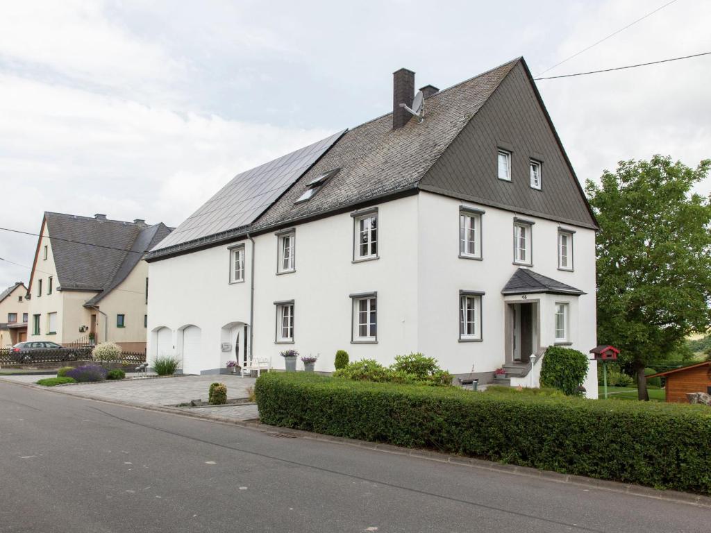 a white house with a black roof on a street at Beautiful Apartment in Morscheid Riedenburg in Morbach