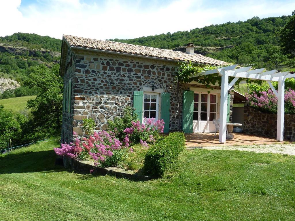 une maison en pierre avec des fleurs devant elle dans l'établissement Beautiful Holiday Home in Saint Pons, à Berzème