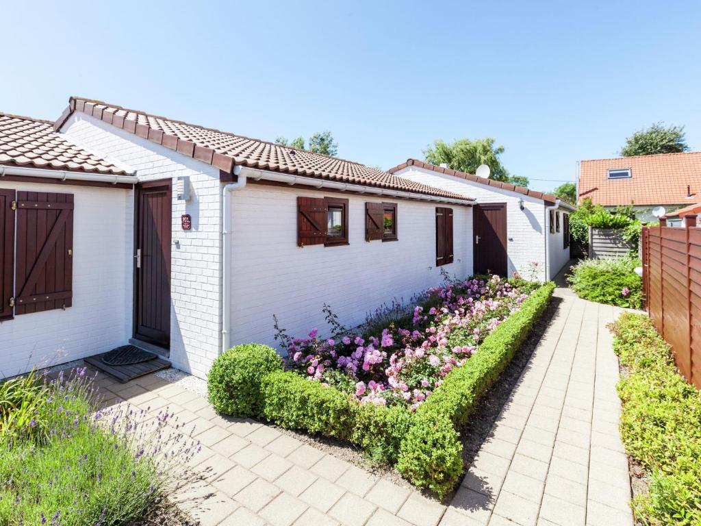 ein weißes Haus mit einem Blumengarten in der Unterkunft This connected holiday home in Bredene