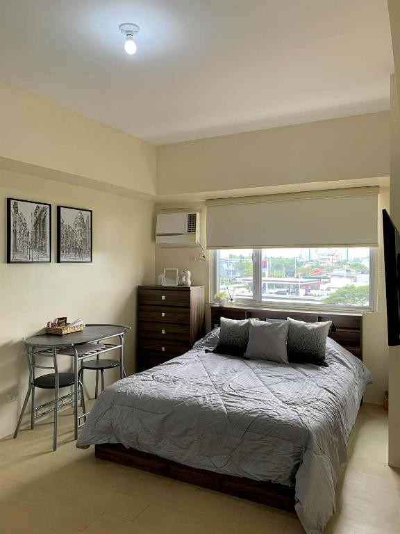 a bedroom with a bed and a desk and a window at Atria Condo in Iloilo City