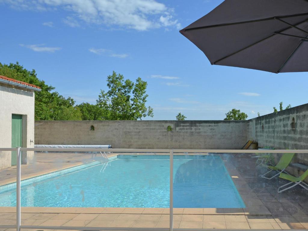 a swimming pool with an umbrella next to a wall at Villa in Saint Privat de Champclos with pool in Barjac