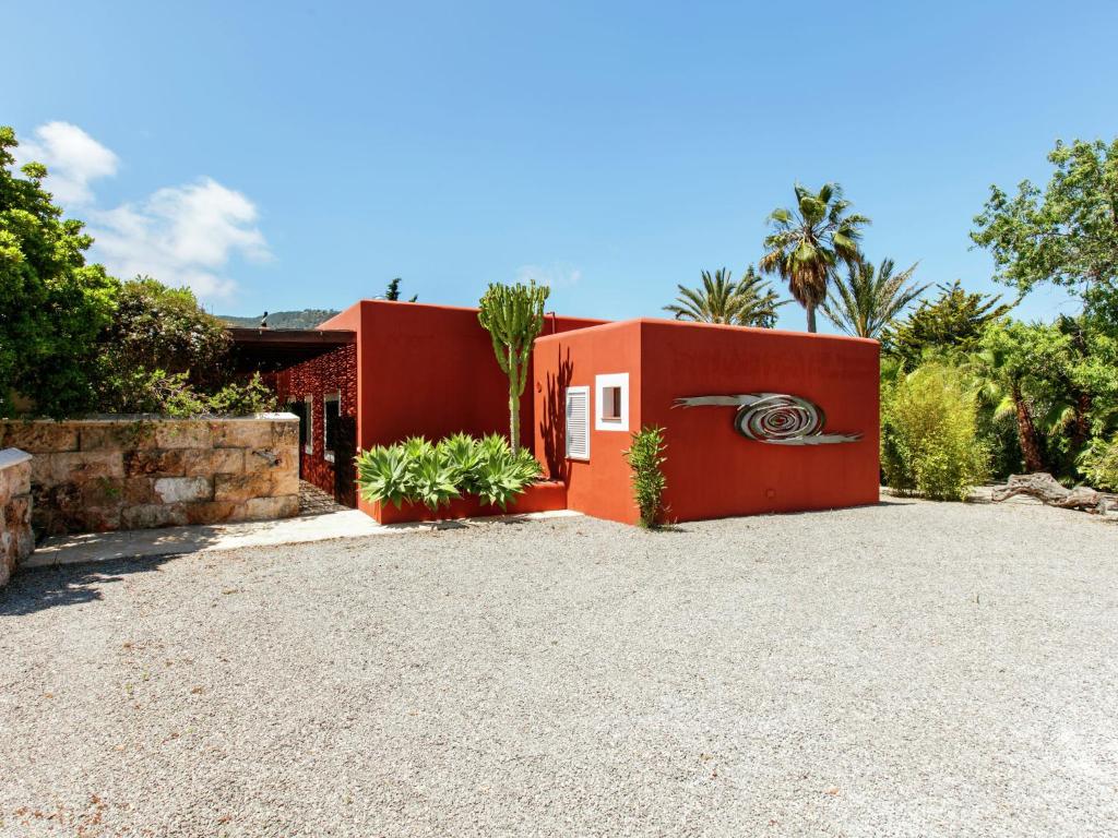a red house with a gravel driveway at Holiday Home in St Josep de sa Talaia with Pool in Sant Josep de sa Talaia
