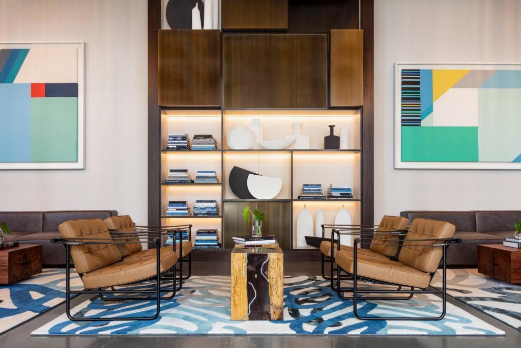 a living room with chairs and a table and shelves at Kimpton - Pittman Hotel by IHG in Dallas