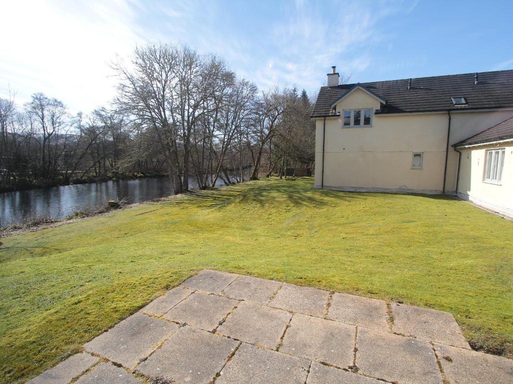 a house with a grassy yard next to a building at Cottage 7 - Skye Cottage - Ukc4884 in Fort Augustus