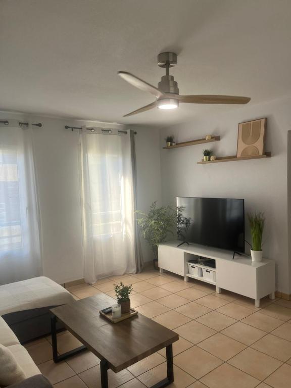 a living room with a flat screen tv and a table at NEW Appart 2 chambres avec piscine proche aeroport in Les Abymes