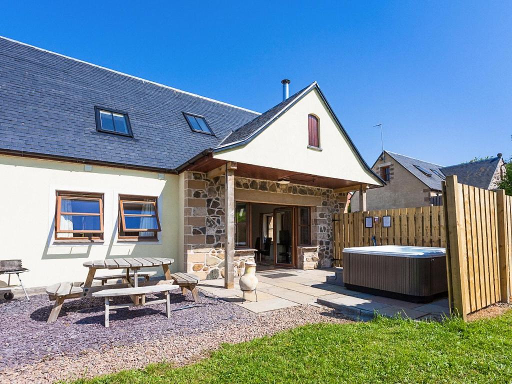 a house with a picnic table and a bath tub at Laurel Cottage - Ukc6256 in Linlithgow