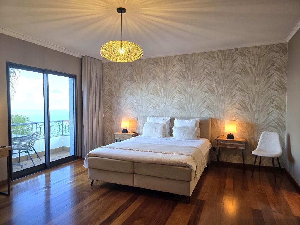 a bedroom with a bed with two lamps and a balcony at Casa do Mundo Madeira in Gaula