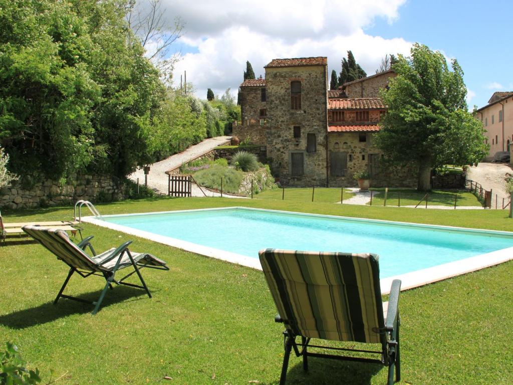 einem Pool mit zwei Gartenstühlen und einem Gebäude in der Unterkunft Belvilla by OYO Le Olive in Vaglia