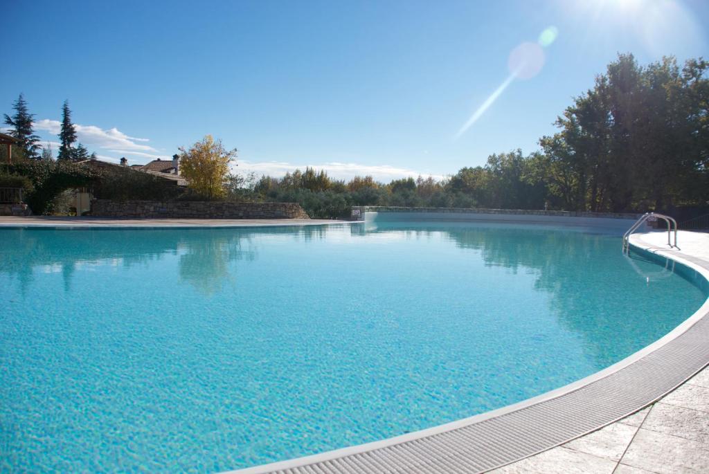a large swimming pool with blue water at Sakura House By Bookinggardalake in Moniga