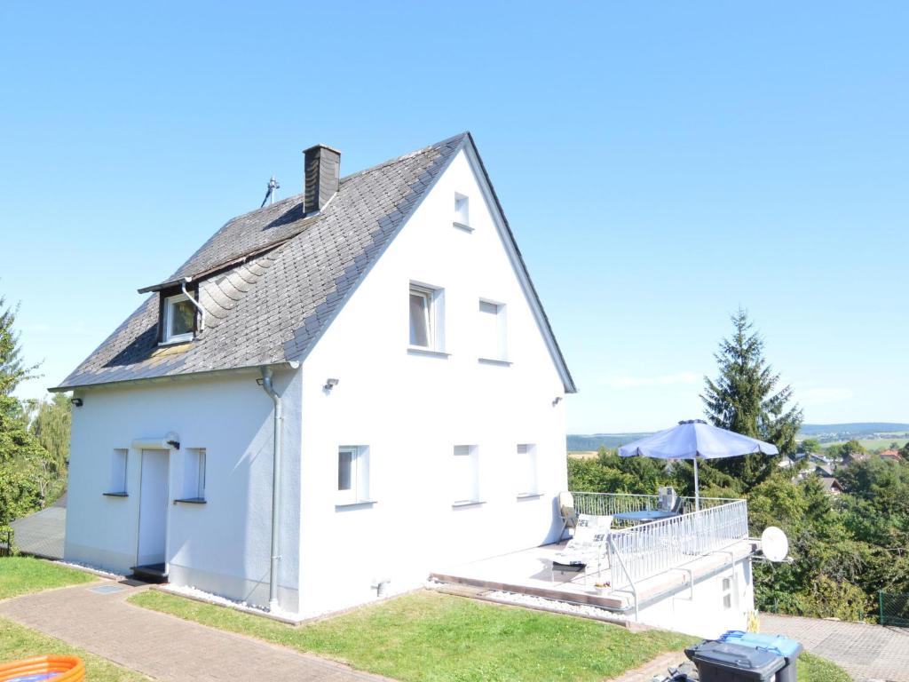 a white house with a table and an umbrella at Peaceful Holiday Home in Rascheid near Forest in Geisfeld