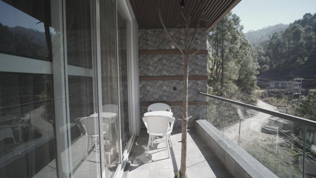 a balcony with white chairs and a view of a mountain at Pine Needles kasauli in Kasauli