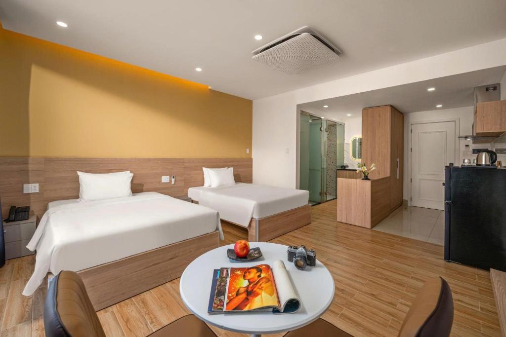 a room with two beds and a table and a kitchen at Mai Living Apartment in Danang