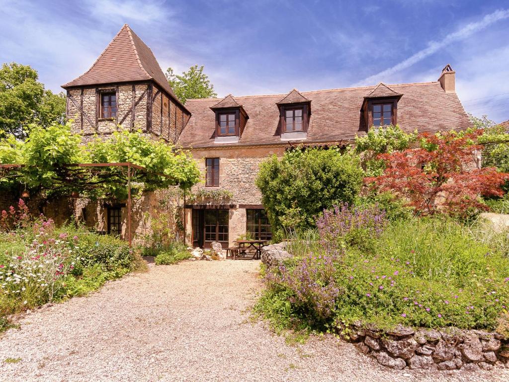 una antigua casa de piedra con un jardín delante de ella en Holiday home in Aquitaine with private garden, en Meyrals