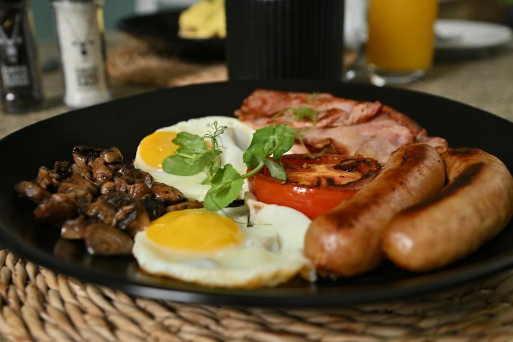 a plate of breakfast food with eggs sausage and tomatoes at Fountains Hotel by Neighbourgood in Cape Town