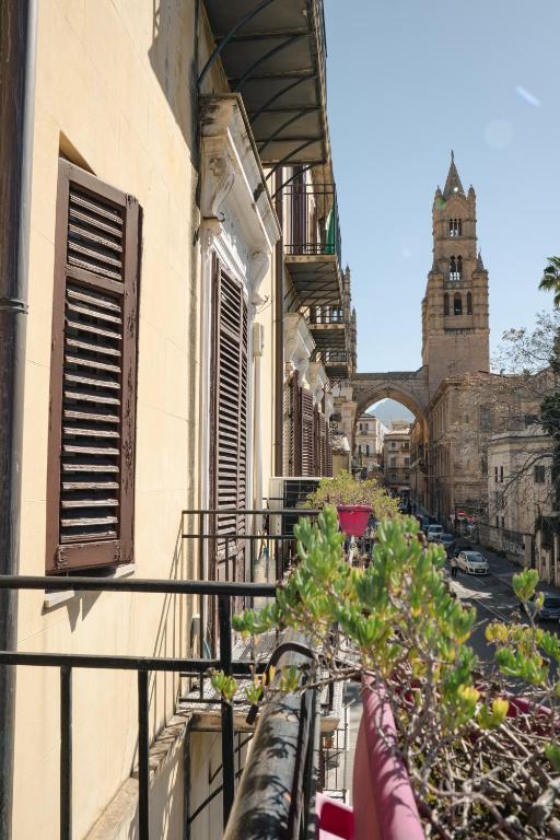 a balcony with potted plants on a building with a clock tower at B&B Matteo Bonello - Fianco Cattedrale in Palermo