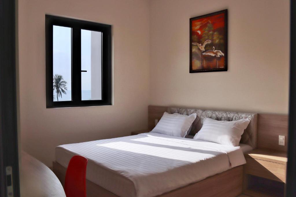 a bedroom with a bed with white sheets and a window at Mui Da Hotel in Phan Thiet
