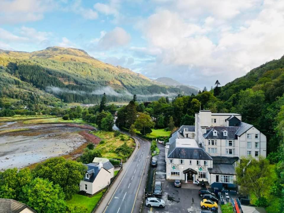 an aerial view of a house with mountains in the background at Loch Long Hotel in Arrochar