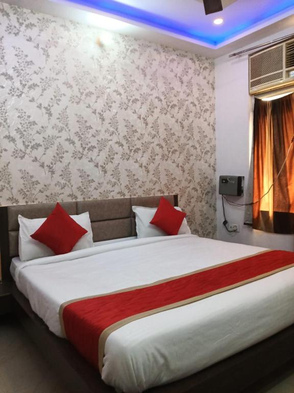 a bedroom with a large bed with red pillows at Hotel Sasa Paradise in Lucknow