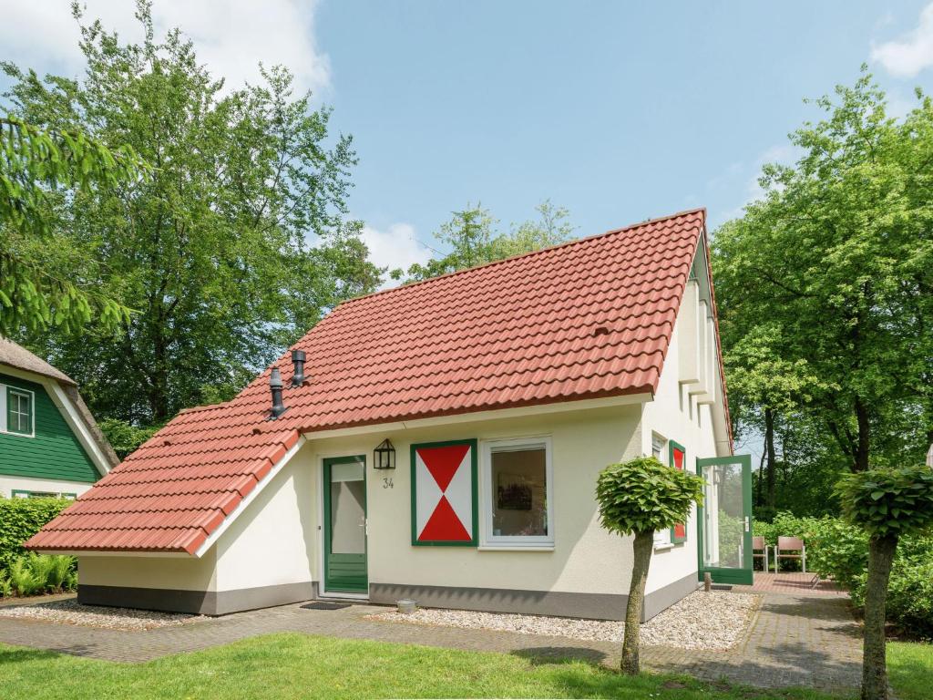 une petite maison blanche avec un toit rouge dans l'établissement Villa with spacious garden near Heeten, à Heeten