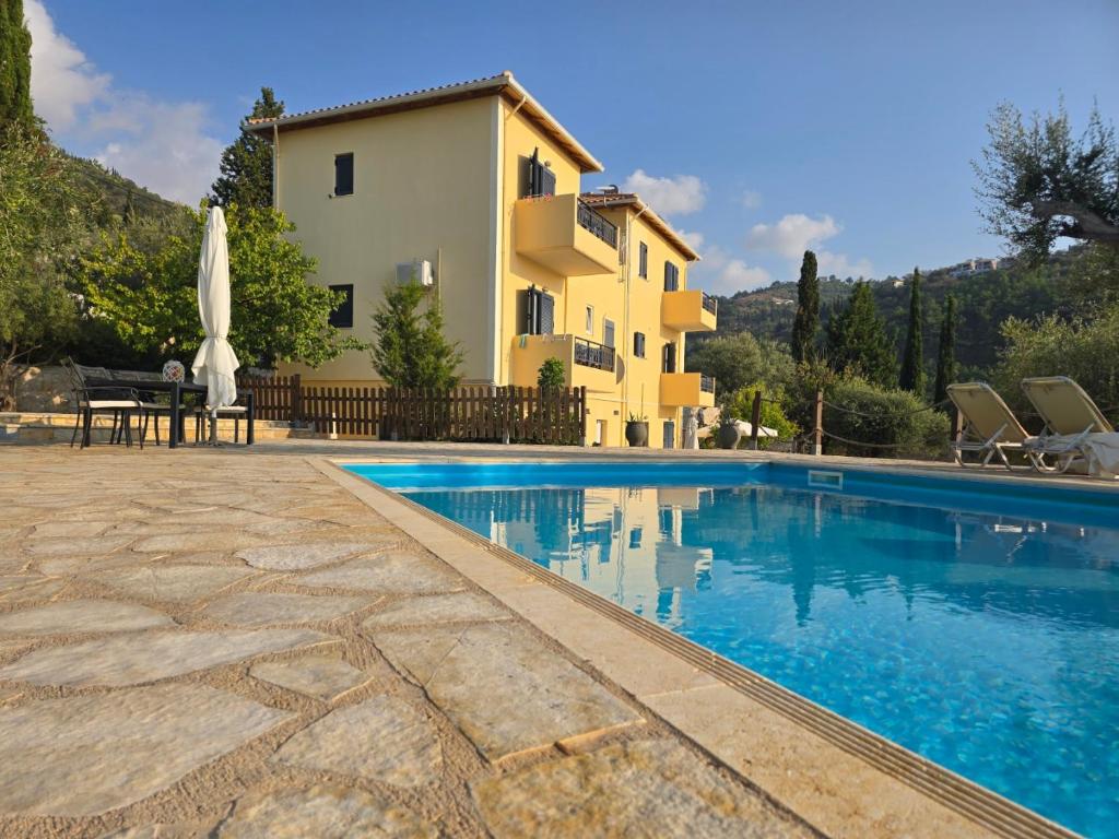 a villa with a swimming pool in front of a house at Sunset View Studios in Agios Nikitas