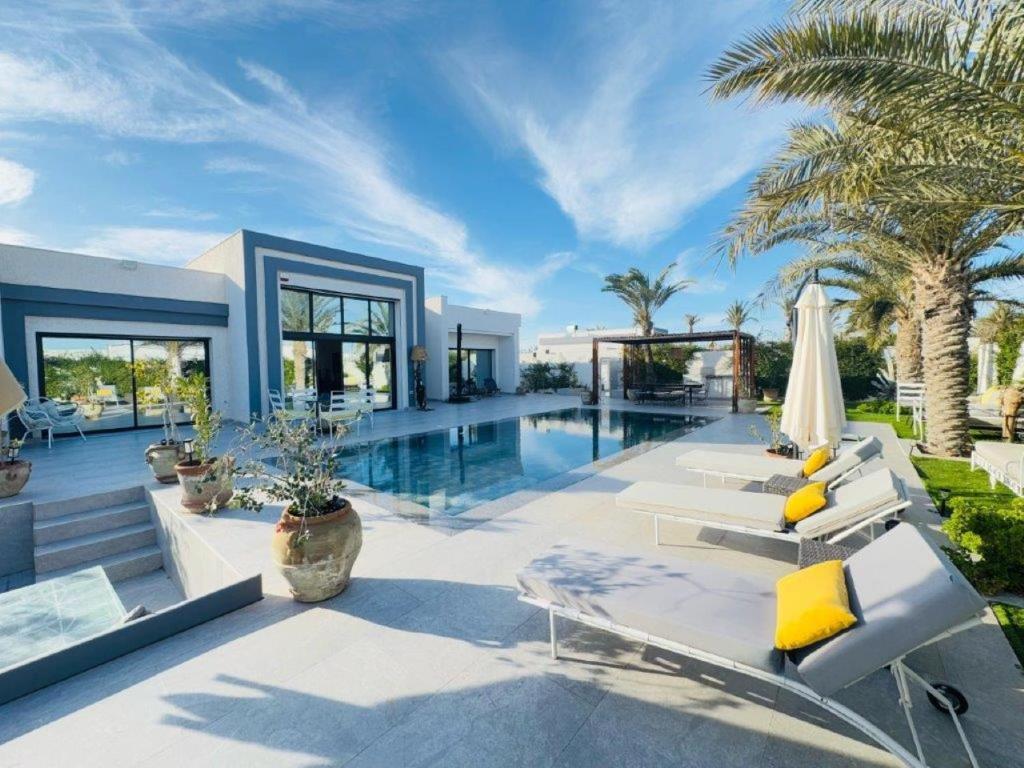 a villa with a swimming pool with chairs and an umbrella at Villa el Kasbah in Midoun