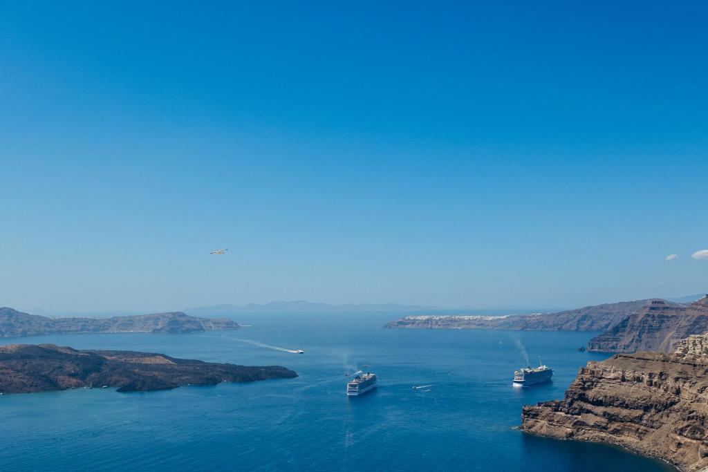 two boats in a large body of water with cliffs at Santorini Gem in Órmos Athiniós