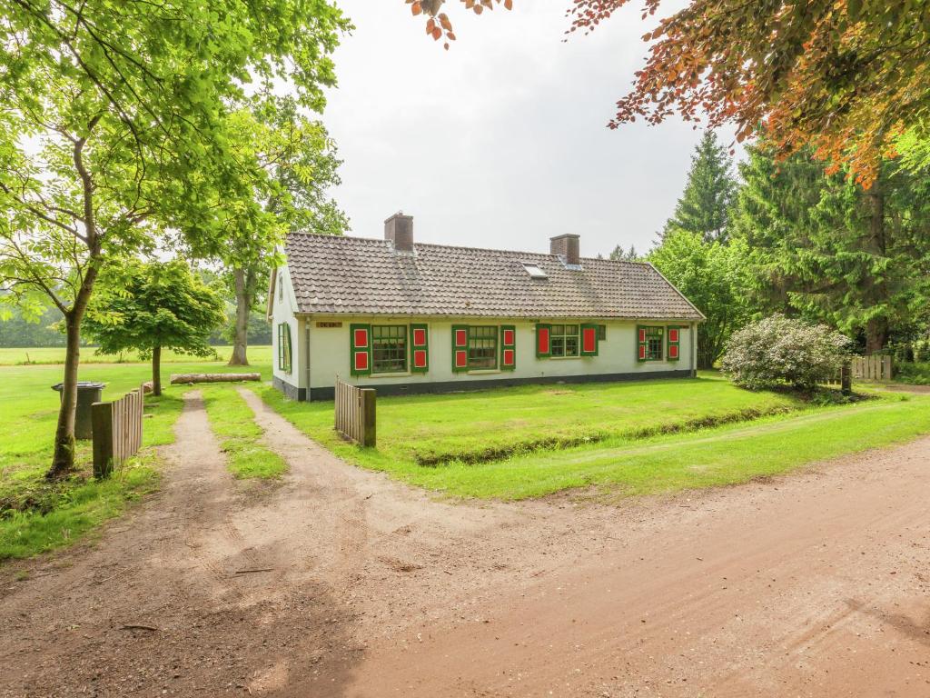 una casa blanca con ventanas rojas y un camino de tierra en Authentic holiday home near Baarn Utrecht on an estate, en Baarn