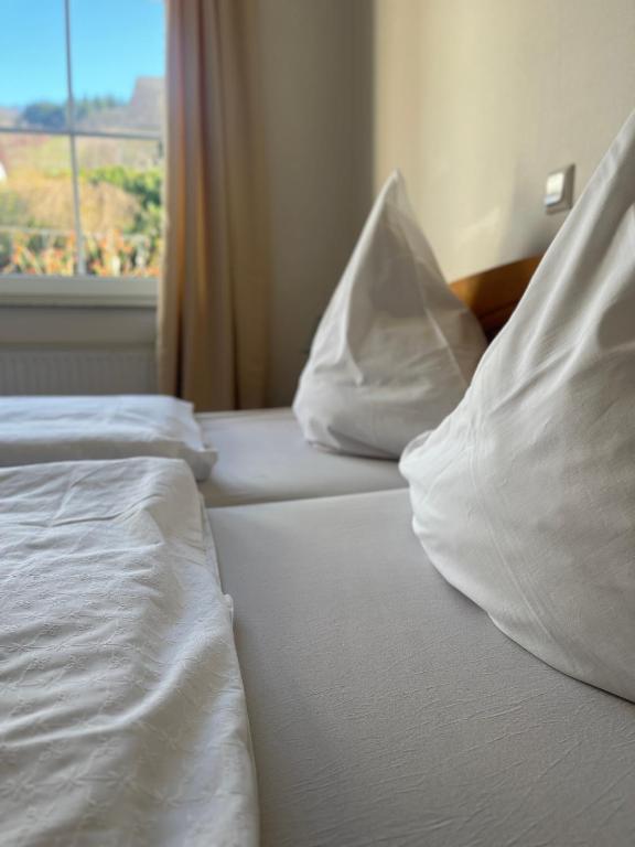 two beds with white sheets and pillows with a window at Weingut Sauer-Kettermann in Enkirch