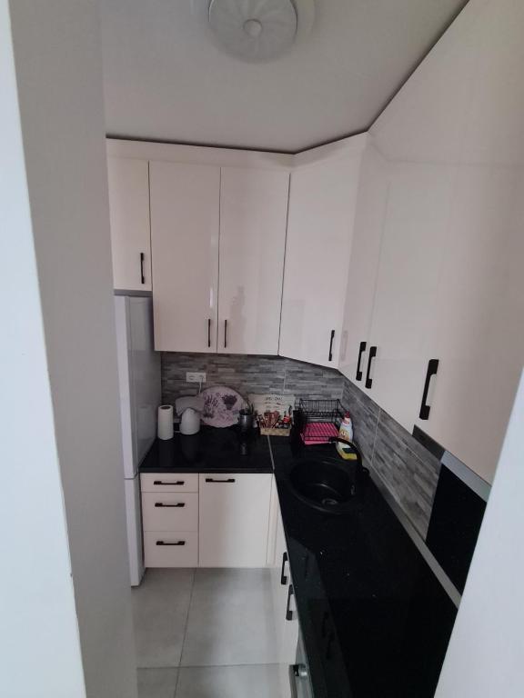 a kitchen with white cabinets and a black counter top at Plavi Safir stan in Bijeljina